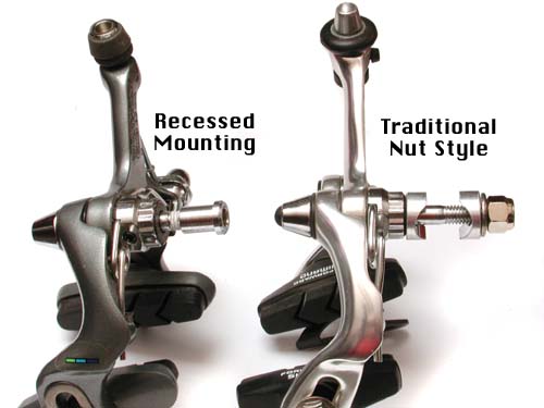 On the left is a modern style brake, with holding nut going into the recessed side of the fork. On the right is the old caliper type, with a longer bolt, and nut fastening on the outside of the fork.