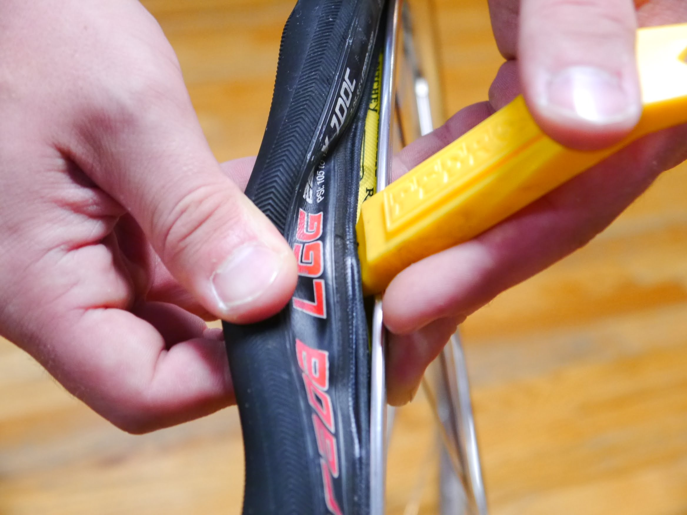 Placing a tire lever: putting it between the tyre and the rim, making sure not to pinch the tube with the lever in the process.