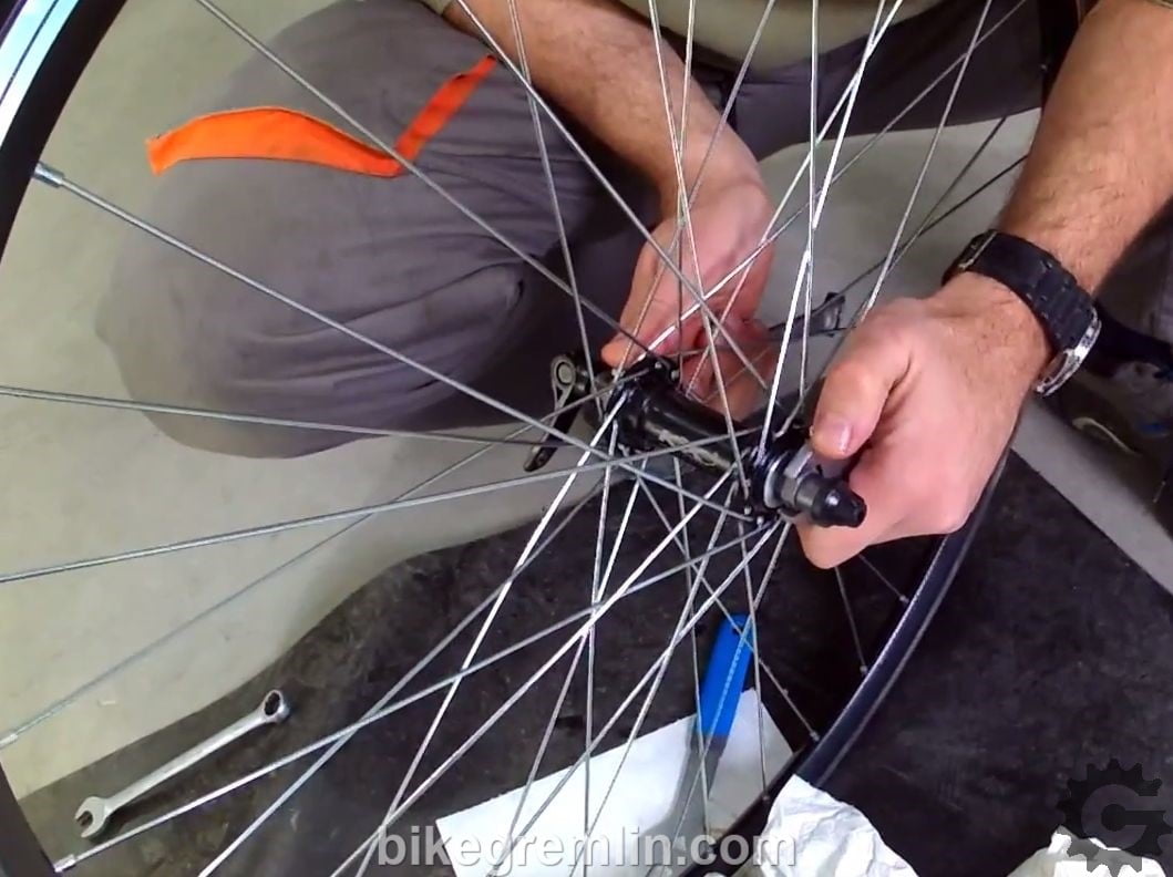 Brute force. One big wrench at each side. The wheel needs to be firmly held with legs and chest to stay in place while doing this. Watch your balance. Locknut will loosen quickly and suddenly!