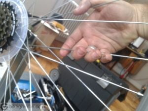 Stress relieving spokes by pulling together two parallel spokes at each side - going all around the wheel at both sides