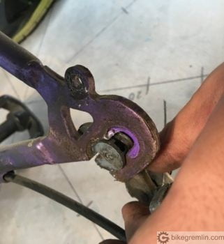 Sliding a hook mounted rear derailleur inside a rear wheel dropout.